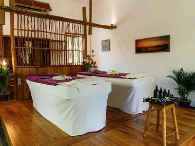 Cozy seating area with white armchairs, wooden floor, and plants in a bright room.