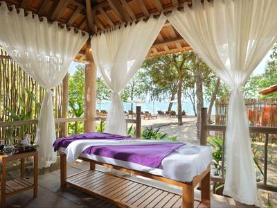 Outdoor spa area with massage table, sheer curtains, and lake view surrounded by trees.