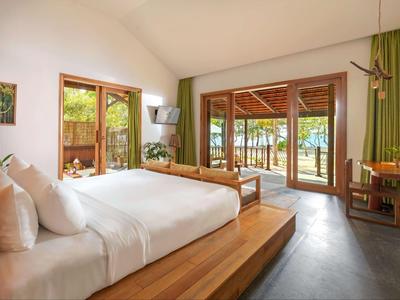 Spacious hotel room with large bed and wooden sliding doors opening to a balcony with lake view.