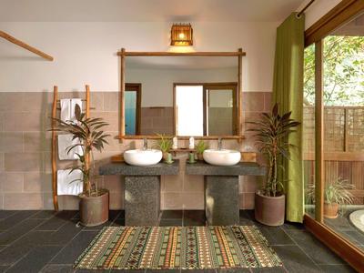 Modern bathroom with double sinks, large mirror, potted plants, and sliding glass door to outdoor tub.