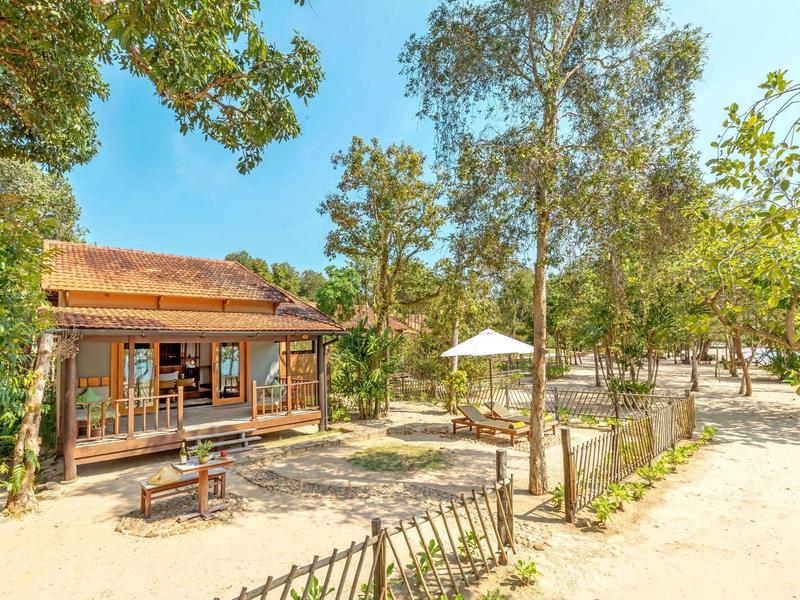 Cozy wooden cabin surrounded by trees with outdoor seating on a sunny day