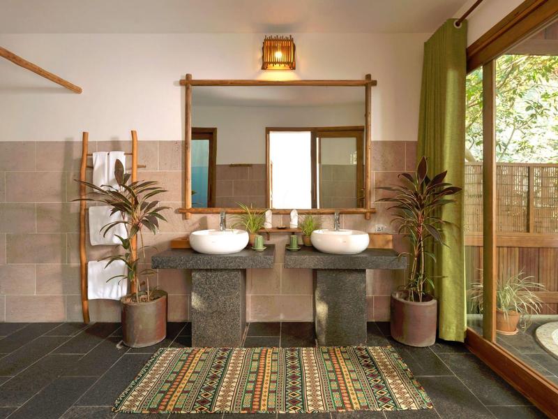 Modern bathroom with double sinks, large mirror, potted plants, and sliding glass door to outdoor tub.