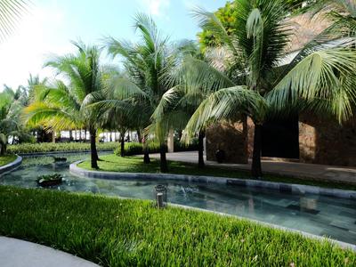 Hotelanlage mit Pool und Palmen unter blauem Himmel