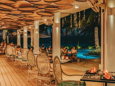 Gemütliche Terrasse mit dekorativen Stühlen und Blick auf beleuchteten Pool bei Nacht.