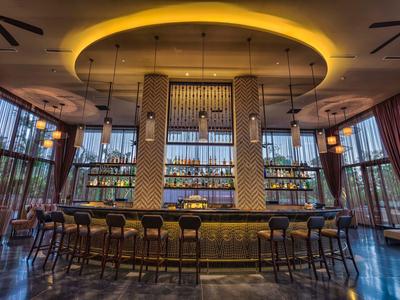 Bar moderna del hotel con luz circular en el techo y varias sillas altas.