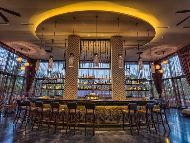 Bar moderna del hotel con luz circular en el techo y varias sillas altas.