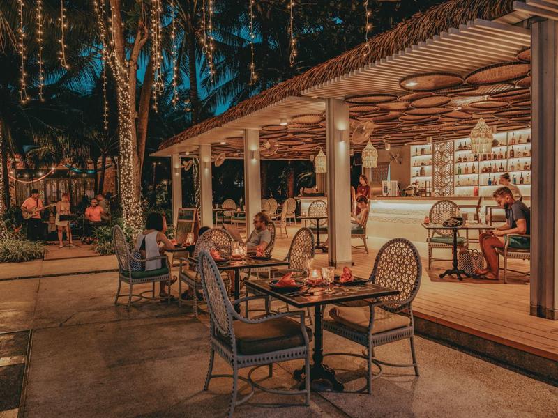Acogedor bar al aire libre en un hotel por la noche con asientos y decoraciones.