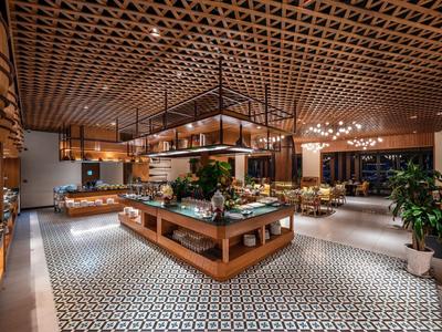 Großer, offener Innenraum eines Restaurants mit geometrischem Bodenmuster und Holzdecke.