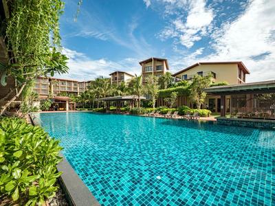 Großer Swimmingpool mit klarem Wasser und angrenzenden Hotelgebäuden unter blauem Himmel.