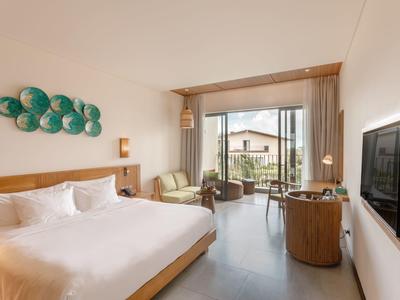 Helles Schlafzimmer mit Doppelbett, grünem Wanddekor, Balkon und modernem Holzinterieur.