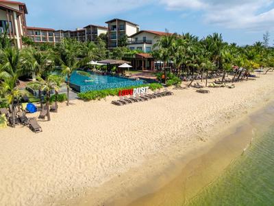 Hotelresort mit Pool, Palmen und Strandliegen an einem ruhigen Sandstrand.