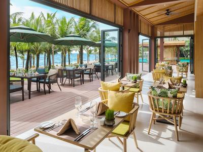 Gemütliches Restaurant mit Holzwänden, gelben Sesseln und Meerblick durch große Glasfenster.