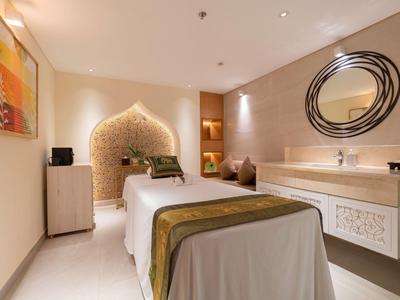 Gemütlicher Behandlungsraum mit Massagebank, warmen Farben und dekorativer Wandgestaltung.