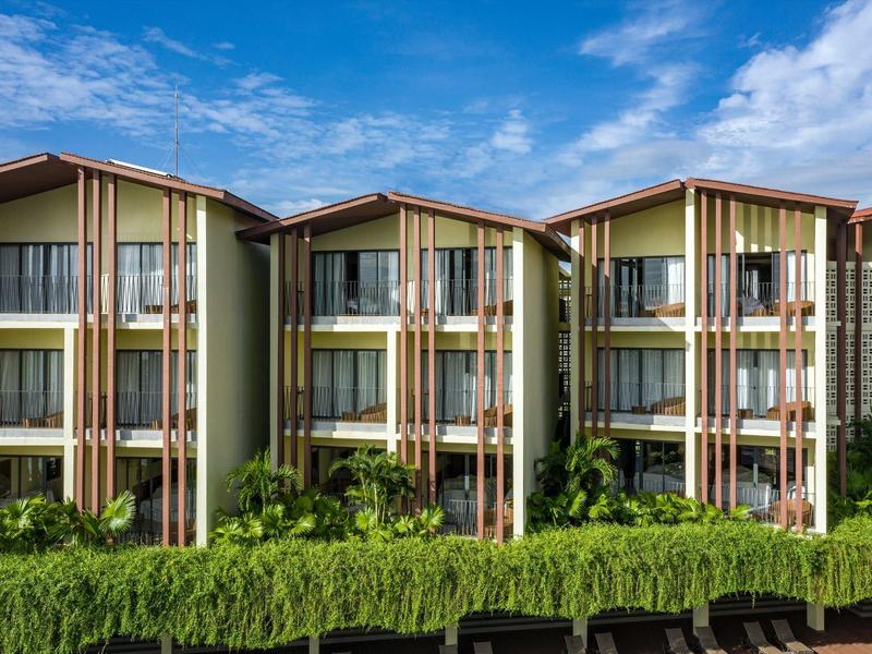 Moderne dreistöckige Wohnhäuser mit großen Fenstern und grünem Vorgarten unter blauem Himmel.