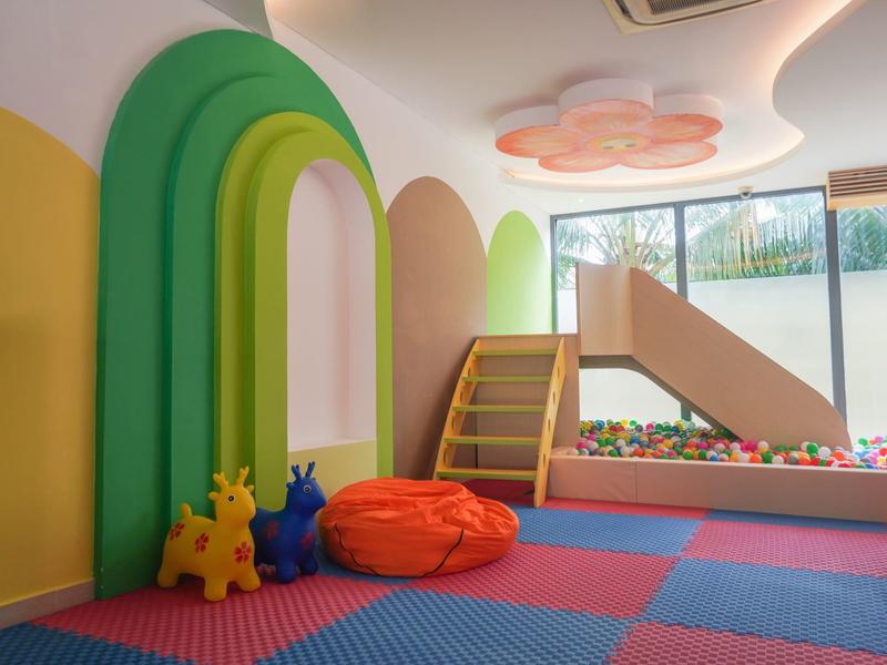 Helles Resort mit Pool, umgeben von grünen Palmen direkt am Sandstrand. Mehrere Gebäude mit roten Dächern.