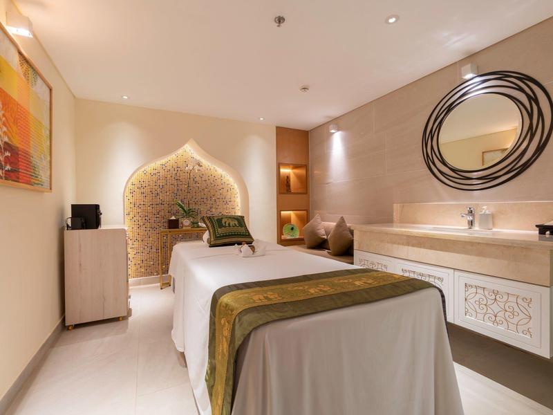 Gemütlicher Behandlungsraum mit Massagebank, warmen Farben und dekorativer Wandgestaltung.