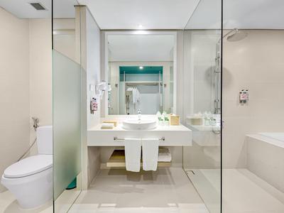 Helle, moderne Badezimmer mit weißer Keramik, Glasabtrennung und hellen Fliesen.