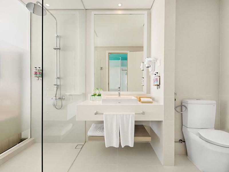 Helles, modernes Badezimmer mit weißem Waschbecken, WC, Duschkabine und Handtuchhalter.