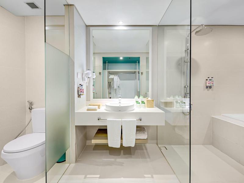 Helle, moderne Badezimmer mit weißer Keramik, Glasabtrennung und hellen Fliesen.