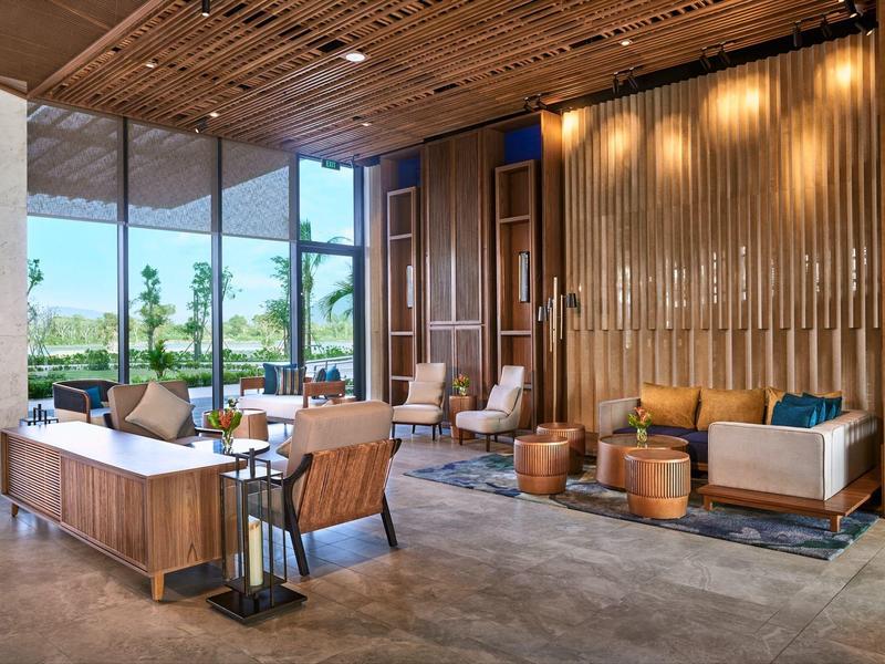 Moderner Lounge-Bereich mit Holzdecke, großen Fenstern, Sesseln und Sofas in warmen Farbtönen.