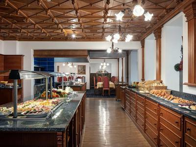 Buffet mit verschiedenen Speisen in einem Restaurant mit Holzboden und dekorativer Holzdecke