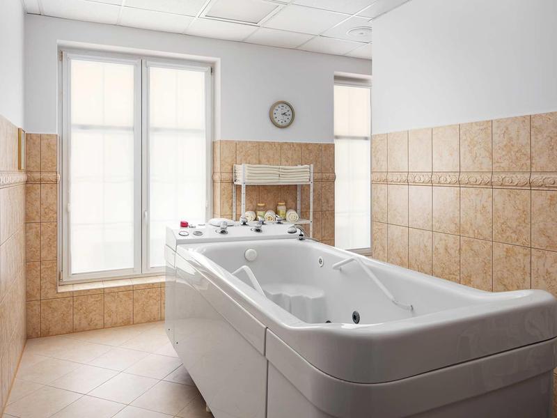 Bright tiled bathroom with large bathtub and window