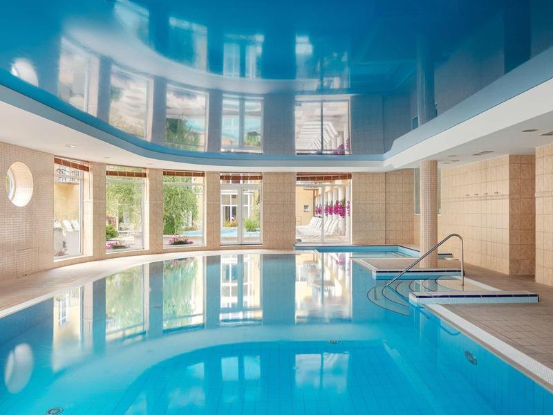 Indoor pool with large windows and modern lighting in a hotel.
