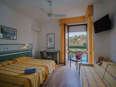 Hotelzimmer mit zwei Betten, einem Schreibtisch, Fernseher und Balkon mit Blick aufs Wasser.