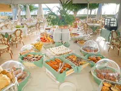 Frühstücksbuffet mit Gebäck, Obst und verschiedenen Aufstrichen in einem hellen Restaurant.