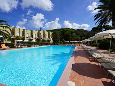 Großer Hotelpool mit Sonnenliegen und grüner Umgebung unter blauem Himmel