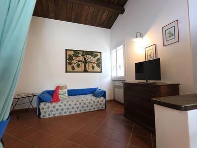 Gemütliches Zimmer mit Schlafsofa, Kommode und Fernseher, helle Wände und Holzbalkendecke.