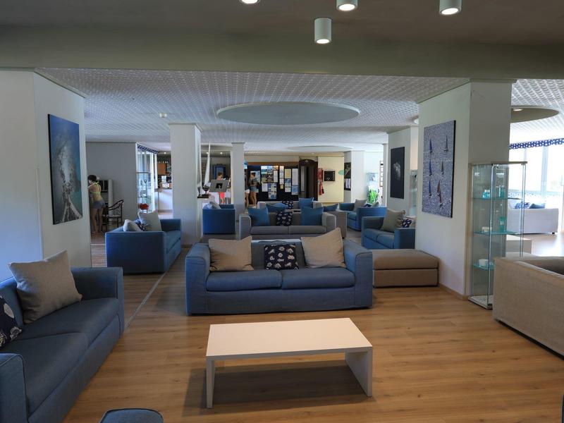 Großer, moderner Aufenthaltsraum mit blauen Sofas, Holzboden und einem Kaffeetisch in einem Hotel.