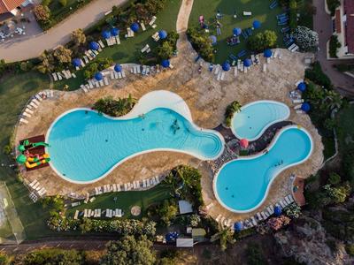 Großer Poolbereich mit mehreren miteinander verbundenen blauen Schwimmbecken und weißen Liegestühlen.