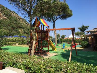 Kinderspielplatz mit buntem Spielhaus, Rutsche und Schaukel auf grünem Untergrund.