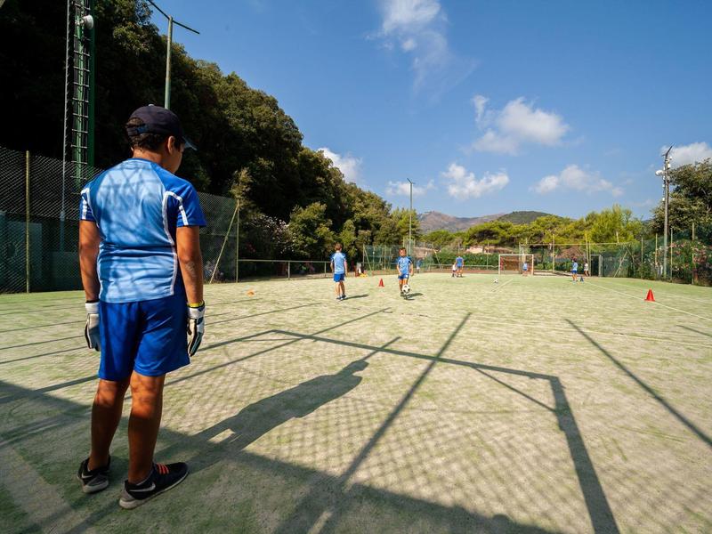 Sportler in blauer Kleidung stehen auf einem Tennisplatz unter klarem Himmel mit Bäumen im Hintergrund.