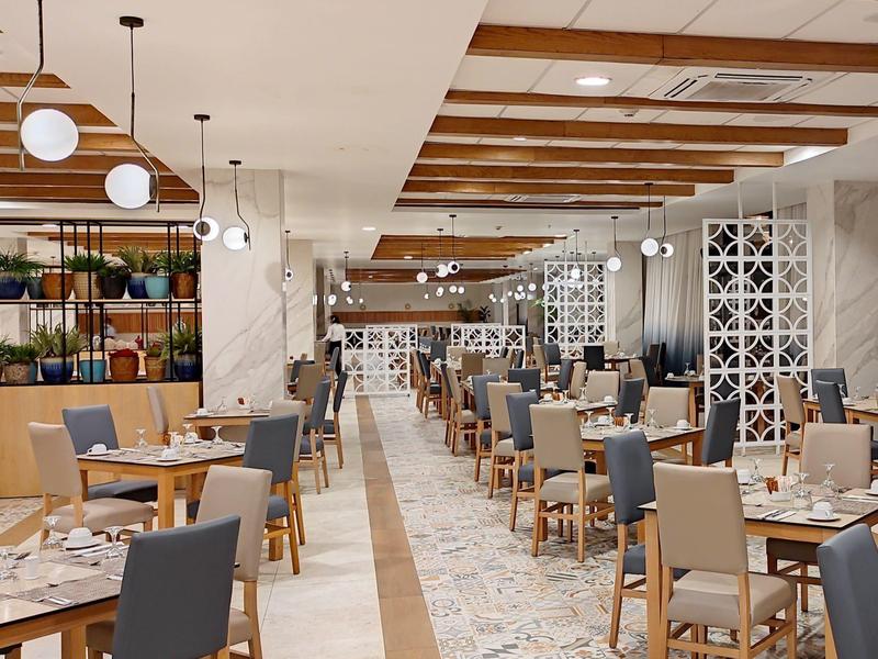 Modern hotelrestaurant met grijze en blauwe stoelen en hangende bolvormige lampen.