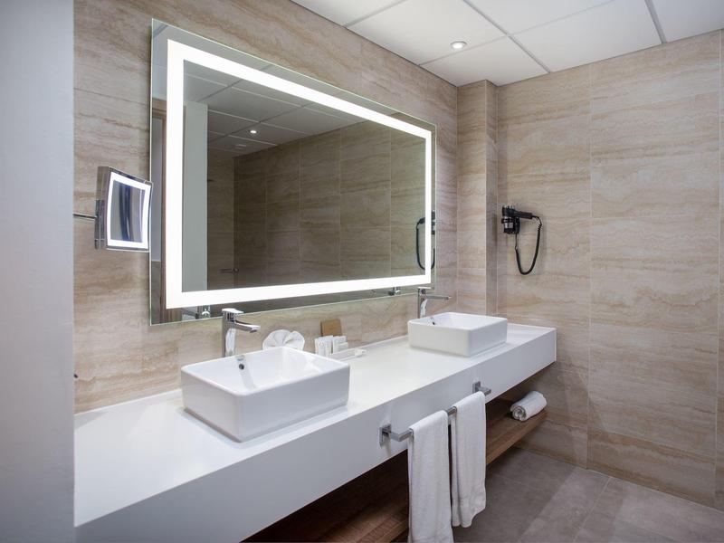 Strand met blauwe ligstoelen en strooien parasols onder palmbomen op wit zand