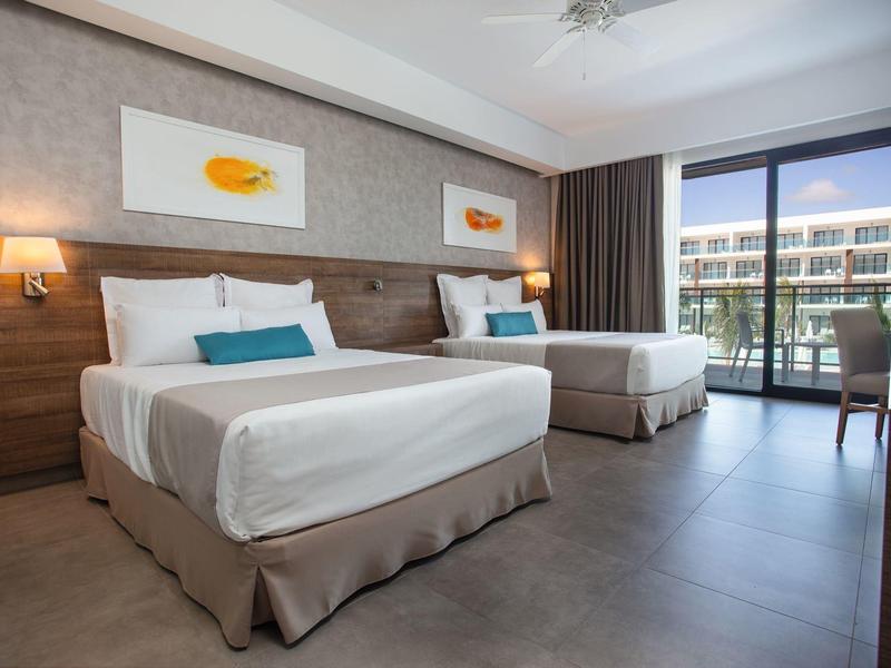 Hotelkamer met twee bedden, modern ingericht en balkon met uitzicht op het hotelzwembad.