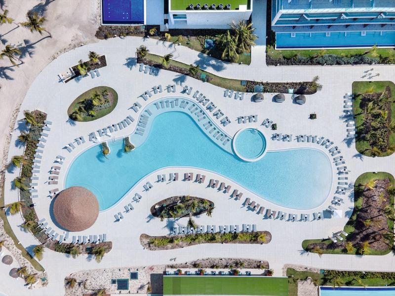 Luchtfoto van een kronkelig zwembad omringd door ligstoelen en appartementen.