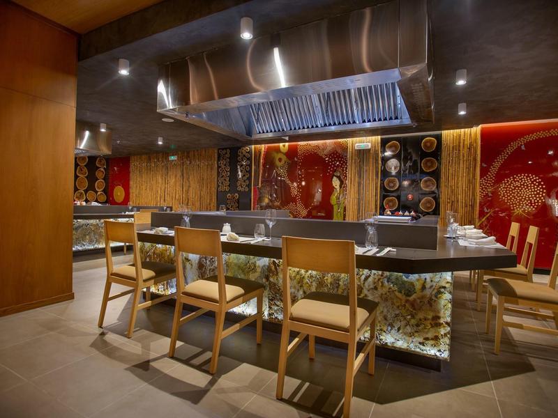 Moderne eetruimte met houten tafel, stoelen en open keuken op de achtergrond.