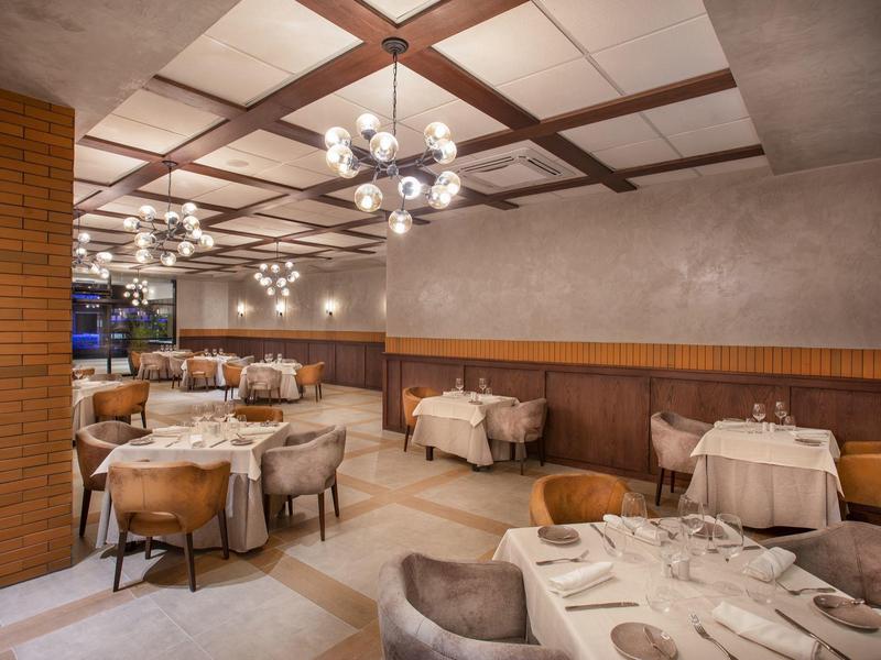 Elegant restaurant met gedekte tafels en moderne plafondverlichting.