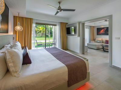 Modern eingerichtetes Hotelzimmer mit Bett, Sitzbereich und Blick auf den Garten.