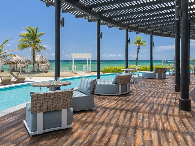 Eleganter Außenbereich mit Sitzgelegenheiten, Pool und Meerblick unter blauem Himmel.