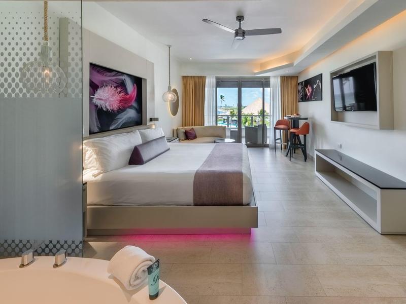 Modernes Hotelzimmer mit großem Bett, Flachbildfernseher und Balkon mit Meerblick.