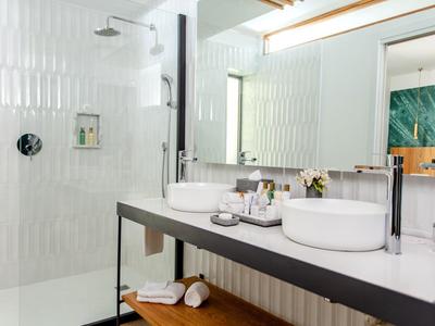 Bagno moderno con due lavandini, grande specchio e doccia a filo pavimento.