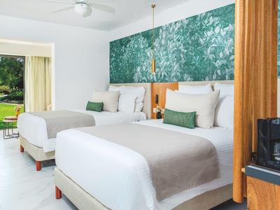 Camera d'hotel con due letti, decorazione verde e vista sul giardino