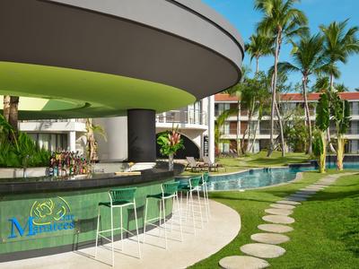 Piscina dell'hotel con bar swim-up, sgabelli bianchi e palme al sole.