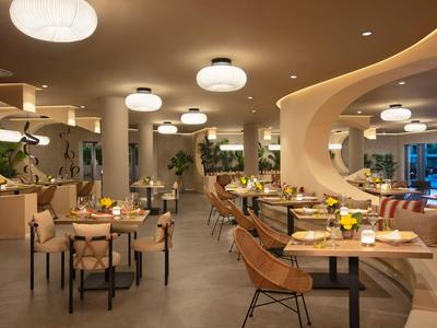 Sala da pranzo moderna con sedie comode, tavoli e illuminazione calda.