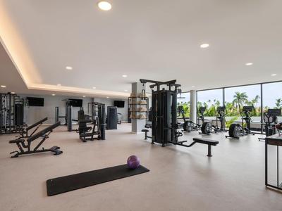 Světle moderní posilovna s velkými okny a výhledem na palmy