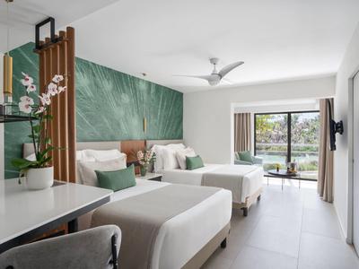 Camera d'hotel moderna con due letti, accenti verdi e grande finestra con vista esterna.